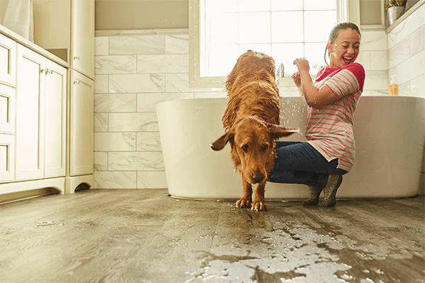 vinyl plank flooring in a bathroom with a dog and girl playing in the bathtub