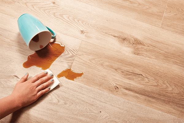 woman's hand wiping up coffee spill from waterproof vinyl plank flooring