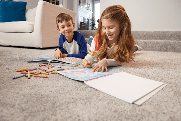 kids laying on carpet drawing with crayons