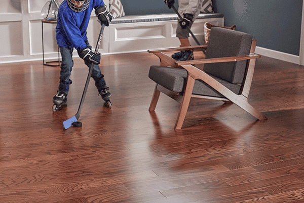 boy playing hockey on hardwood flooring in a living room