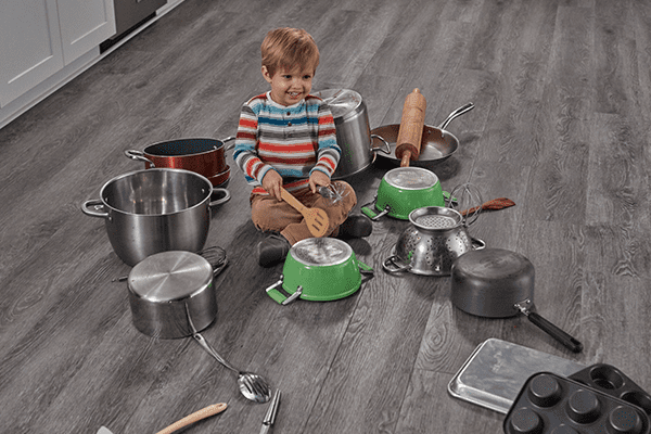 toddler playing with pots on vinyl plank flooring in a kitchen