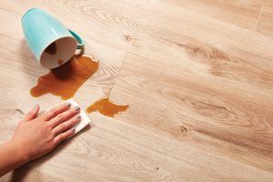 coffee spill being cleaned from 100% waterproof vinyl plank flooring