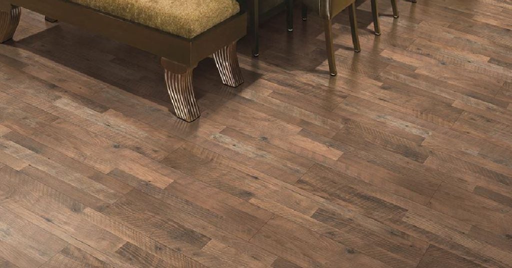 Rustic home - laminate flooring in shades of brown and grey with furniture legs visible, suggesting a cozy, homey interior.