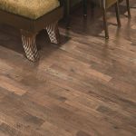 Rustic home - laminate flooring in shades of brown and grey with furniture legs visible, suggesting a cozy, homey interior.